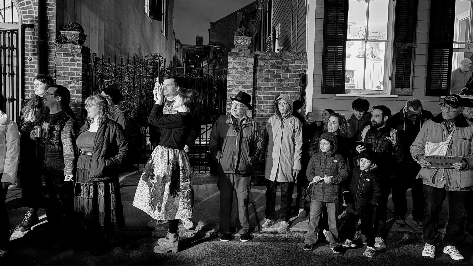 a black and white photo of people in the French Quarter lined up waiting for a parade